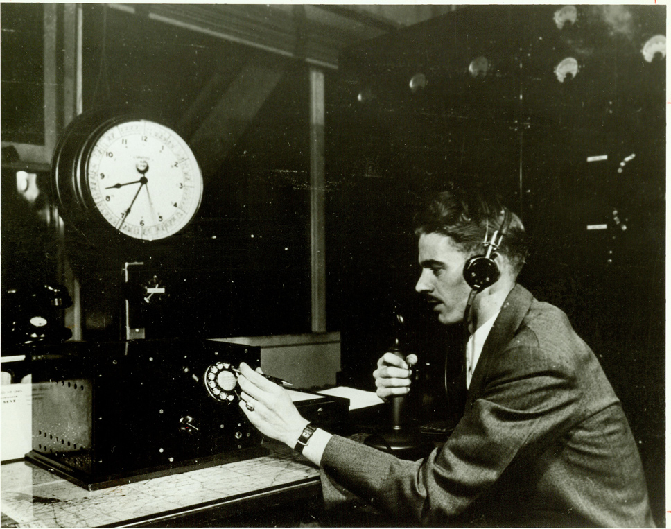 Historical black and white image of a dispatcher using an old phone